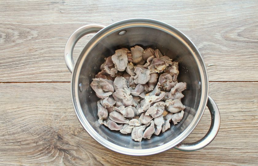 1. Этап. Сырный суп с куриными желудками: Куриные желудки разрежьте на 2-3 части, промойте и выложите в кастрюлю с толстым дном. Залейте желудки водой и доведите до кипения на среднем огне. Слейте первую воду из кастрюли, промойте желудки и залейте холодной водой. Поставьте на средний огонь и варите в течение одного часа, до готовности желудков.