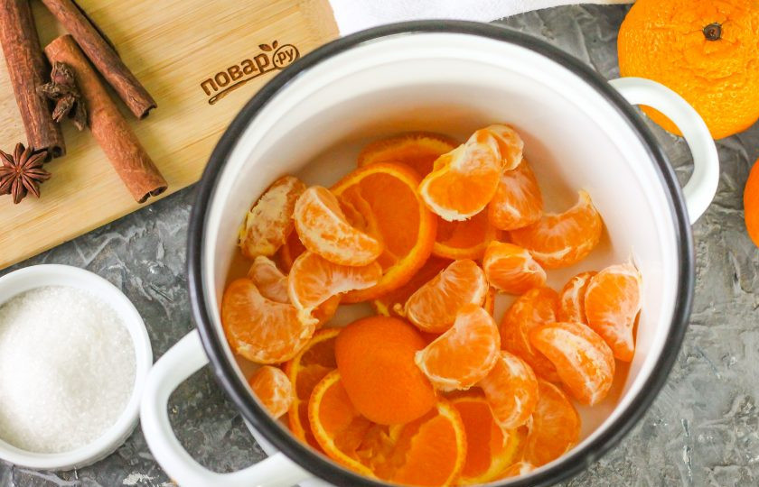 1. Этап. Зимний мандариновый напиток: Мандарины ошпарьте кипятком, один из них нарежьте кружочками вместе с кожурой, остальные очистите и отделите дольки друг от друга. Выложите нарезки цитрусовых в кастрюлю или ковш.
