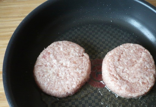 1. Этап. Двойной чизбургер Чили с жареным луком: В большой сковороде на умеренно сильном огне нагрейте растительное масло и положите две котлеты, слегка прижмите их металлической лопаткой.