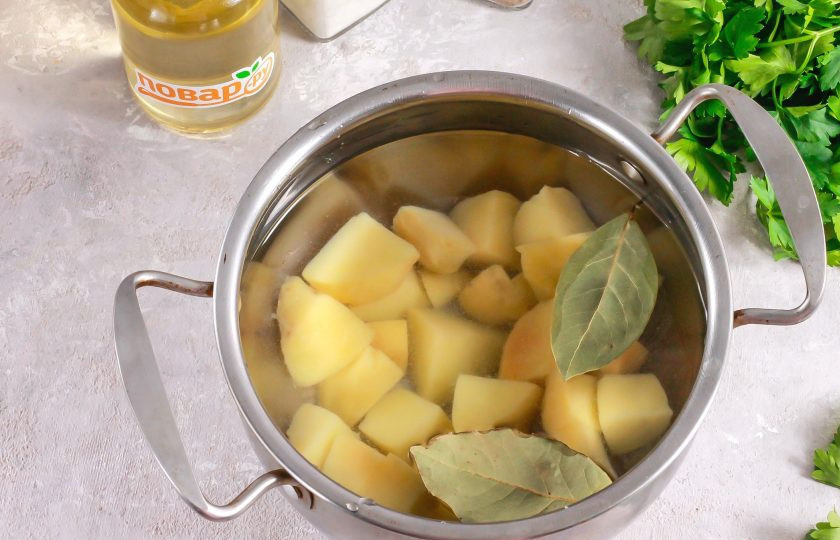 1. Этап. Суп из сельдерея с беконом: Картофель нарежьте средними кубиками и высыпьте в кастрюлю, казан. Добавьте лавровые листья и влейте теплую воду. Поместите емкость на плиту и отварите все примерно 15 минут.
