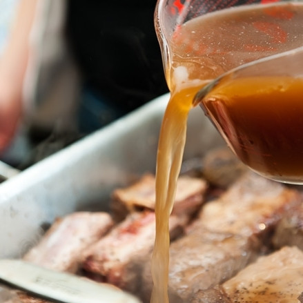 1. Этап. Тушеные говяжьи ребрышки: 6. В сковороду или противень к ребрышкам добавьте бульон. Его надо столько, чтобы почти покрыть ребрышки. Верхушка пусть торчит 