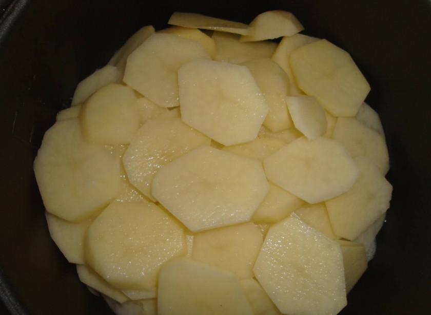1. Этап. Говядина в мультиварке Панасоник: Тонкими кружочками нарежьте картофель, выложите его на лук.