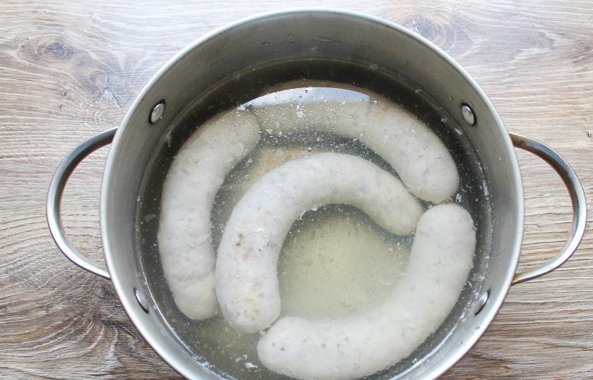 1. Этап. Домашняя колбаса на сковороде: Налейте в кастрюлю воду и посолите. Доведите до кипения, убавьте огонь до минимального. В колбасе сделайте проколы по всей поверхности. Выложите ее в воду и варите в течение 5 минут.