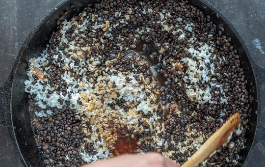 1. Этап. Чечевица черная на сковороде: Теперь заливаем лук водой, доводим до кипения. Отправляем промытый рис и чечевицу в сковороду и готовим, постоянно помешивая.