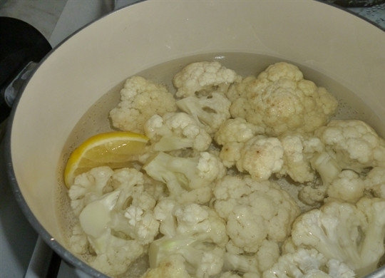 1. Этап. Цветная капуста в яйце и сухарях: Для начала нам необходимо разобрать цветную капусту на соцветия и хорошенько их промыть. Затем наливаем в кастрюлю два литра воду, ставим на огонь, а когда она закипит, добавляем соль и лимон. Выкладываем капусту в кипящую воду и варим в течение 15 минут - для нее этого времени будет вполне достаточно.