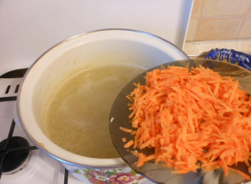 1. Этап. Щи без картошки: Поставьте бульон на огонь, дайте ему закипеть. Тем временем натрите морковку на крупной терке. Бросьте в кипящий бульон морковку.