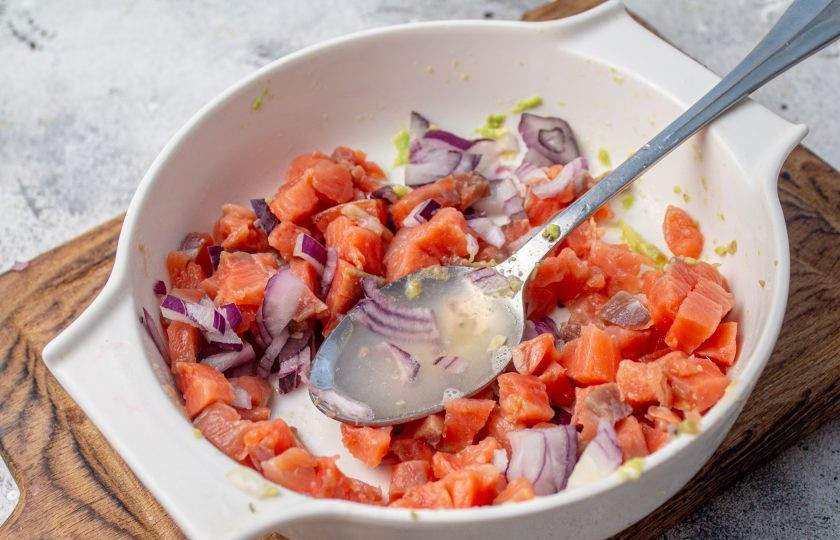 1. Этап. Праздничный легкий салат с семгой и авокадо: Оставшуюся половину луковицы нарежьте мелко, выложите отдельно от авокадо. Семгу снимите с кожи, если есть, достаньте косточки. Мякоть рыбы нарежьте мелким кубиком, добавьте ее к луку, влейте лимонный сок и перемешайте.