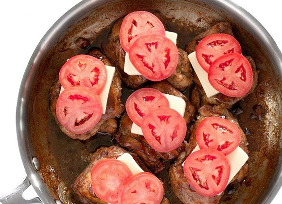 1. Этап. Куриные бедра с сыром и томатами: 6. Верните в сковороду с образовавшимся соусом мясо и полейте каждый кусочек соусом. Выложите на мясо сыр, а затем — ломтики томата.