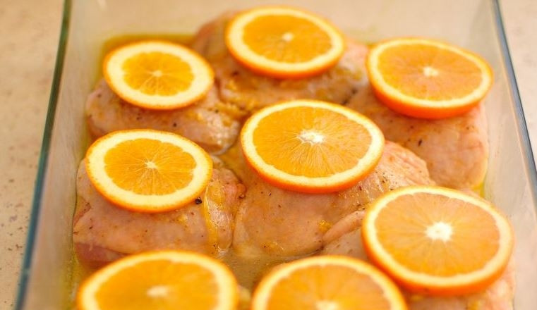 1. Этап. Рецепт курицы с апельсинами в духовке: Замаринованную курицу достаньте из холодильника. Апельсин вымойте, обсушите и нарежьте колечками около сантиметра шириной. Выложите по одному кружочку апельсина на каждый кусочек курицы.