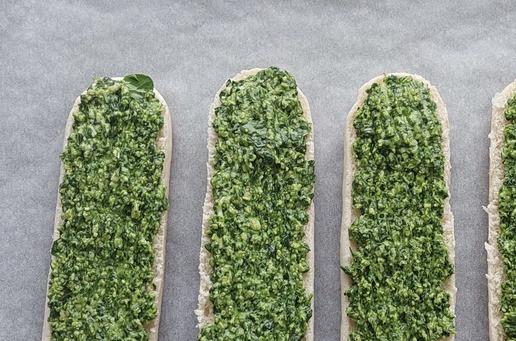 1. Этап. Булочки, запеченные со шпинатом и сыром: Булочки для хот-догов разделить пополам, переложить на противень, застеленный бумагой для выпечки. Распределить шпинатную массу.