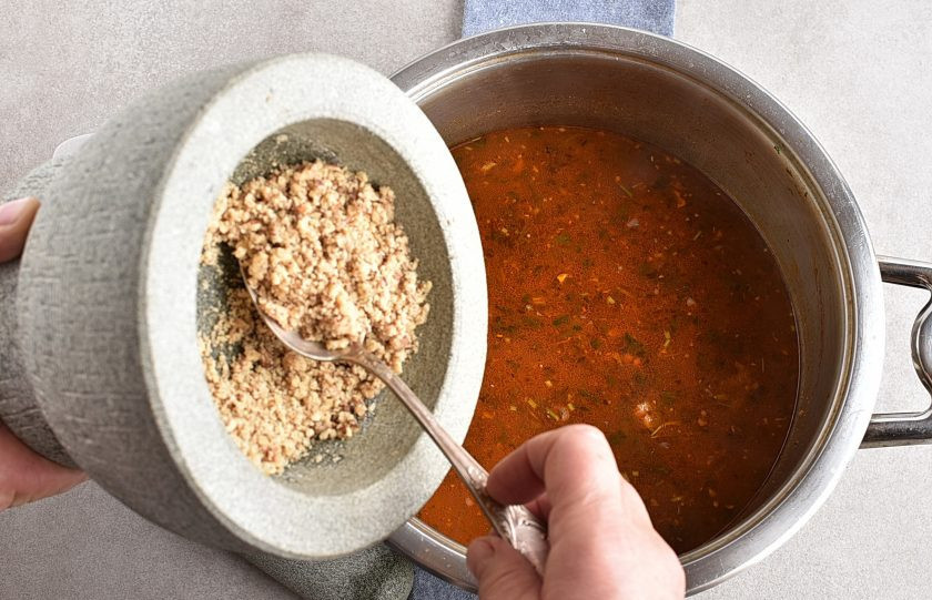 1. Этап. Харчо из говядины с ткемали: Опустите в бульон пассеровку. Добавьте толченые орехи и перемешайте.