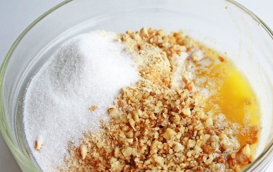 1. Этап. Новогодний чизкейк с клюквой: 1. Сразу же включайте духовку, чтобы она успела разогреться до 180 градусов. Для коржа соедините в глубокой мисочке измельченное в крошку печенье, сахар, растопленное масло и по желанию добавьте горсть орехов. Все как следует перемешайте.