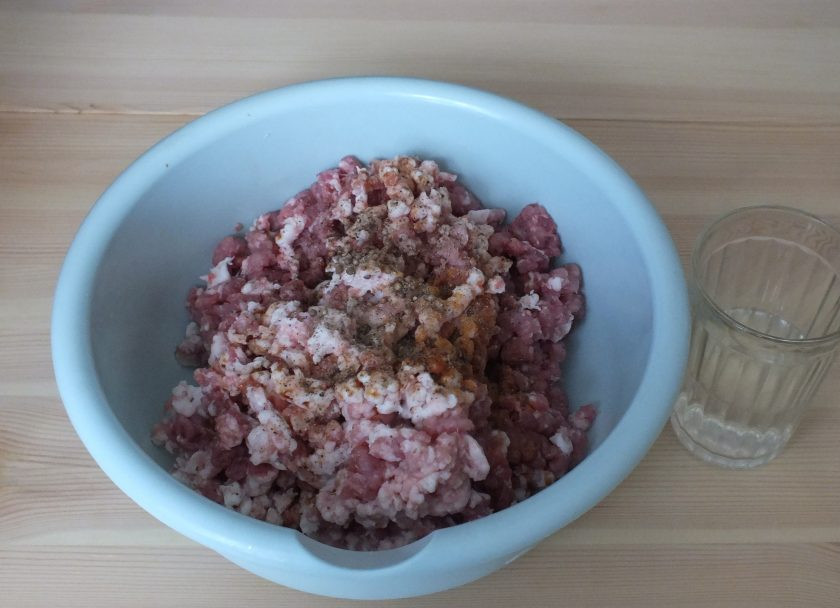 1. Этап. Домашняя колбаса в фольге: В полученный фарш добавьте все перцы, кориандр (половину всыпать семенами, половину измельчить), соевый соус, холодную воду.