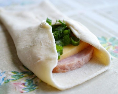 1. Stage. Cheese Puff Pastry Envelopes: Cut the ham and cheese into slices, chop the greens. Cut the roll into pieces and roll, lay ham and cheese in the center of the dough, sprinkle with greens on top and pinch the edges.