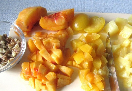 1. Этап. Фруктовый салат с брынзой и орехами: Персики и абрикосы можно брать свежие или консервированные. Здесь использую половинки консервированных абрикосов, а персик свежий, его вымыть, разрезать пополам и удалить косточку. Фрукты нарезать на маленькие кусочки. Консервированные ананасы достать из банки, дать стечь жидкости и мелко нарезать. Орехи измельчить (потолочь).