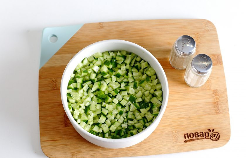 1. Этап. Салат с копченой грудкой и сыром: Сверху распределите нарезанный примерно такими же кубиками огурец. Поперчите и посолите огурец по вкусу.