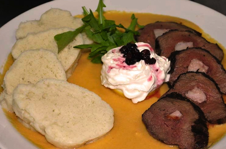 1. Этап. Свичкова на сметане: Говяжий рулет нарежьте кусочками около двух сантиметров толщиной. На дно блюда выложите овощное пюре так, чтобы то полностью закрыло дно. На одну часть блюда выложите мясо, а вторую часть заполните кнедликами.