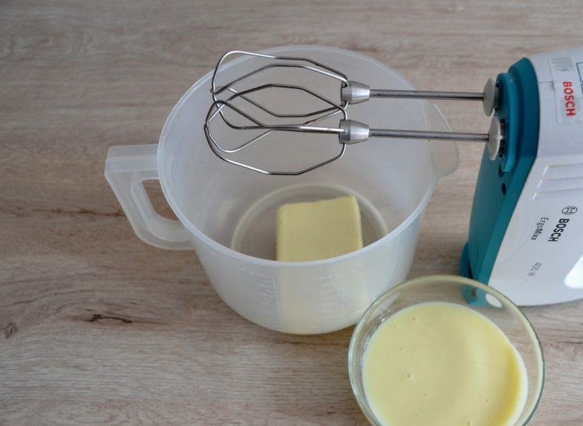 1. Этап. Профитроли с масляным кремом: Пока выпекаются профитроли, займитесь приготовлением масляного крема. Для этого сначала взбейте сливочное масло комнатной температуры до пышности. Затем постепенно вливайте сгущенное молоко, которое тоже должно быть комнатной температуры. Продолжайте взбивать до пышности.