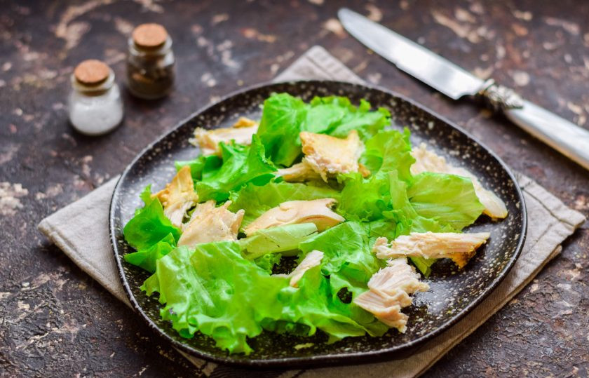 1. Этап. ПП Цезарь с курицей: Салатные листья сполосните, просушите, порвите и выложите на тарелку. Заранее запеките филе курицы, немного остудите и крупно нарежьте, добавьте к листьям.