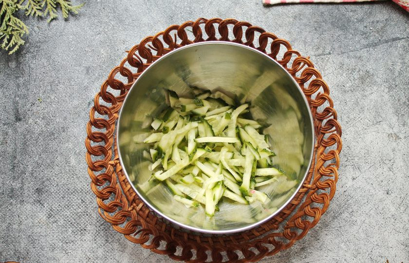 1. Этап. Салат с огурцом, кальмаром и яблоком: У свежего огурца отрежьте кончики и порежьте соломкой. Выложите огурец в салатник.