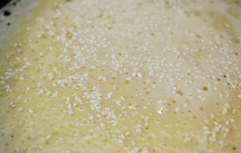 1. Этап. Творожные блины с кунжутом и изюмом: 5. Добавьте в тесто растительное масло и выпекайте. Сковороду смажьте маслом, налейте половником тесто, равномерно распределите по сковороде и сразу посыпьте кунжутом. Затем переверните блин и запеките с другой стороны.