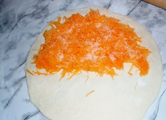 1. Этап. Плацинды с тыквой: 4. Раскатываем каждую часть и на один край выкладываем тертую тыкву, посыпав ее сахаром. Теперь нужно слепить очень хорошо края. Плацинды в молдавской кухне раскатываются так же, только начинка выкладывается по центру и края слепливаются с 4 частей к центру.