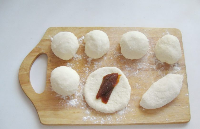 1. Этап. Жареные пирожки со сливовым джемом: Каждый шарик раскатайте в лепешку, на середину которой выложите порцию джема. У меня сливовый, но можно взять любой по вкусу. Слепите края лепешки, формируя пирожок.