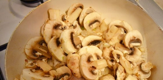 1. Этап. Кальмары, тушенные с шампиньонами: Шампиньоны помойте, нарежьте пластинками. Лук почистите, измельчите. Разогрейте масло на сковороде. Выложите в неё лук и грибы. Включите средний огонь. Как грибы пустят сок, убавьте огонь и готовьте 4 минуты.