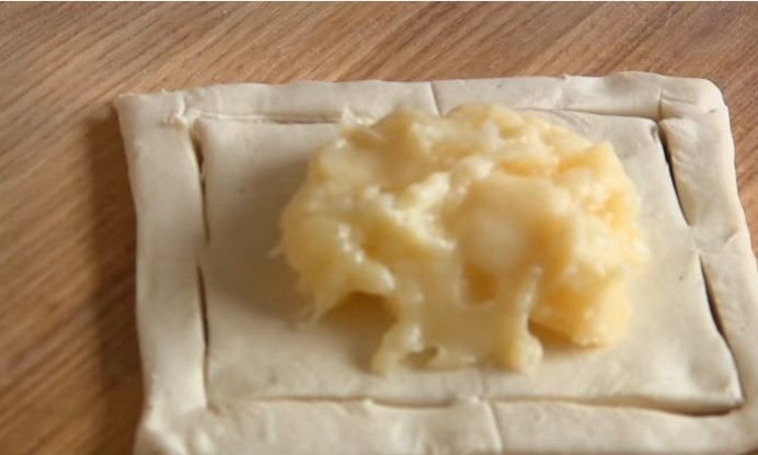 1. Этап. Слойки из слоеного теста с кремом Патисьер: 6. Выложите в центр квадрата крем, соедините два противоположных уголка теста. Предварительно смочите уголки водичкой.