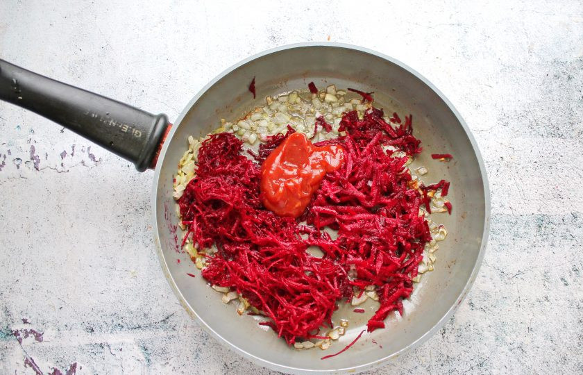 1. Этап. Борщ из оленины: Вторую свеклу натрите на средней или крупной терке и выложите к обжаренному луку. Добавьте томатную пасту, влейте уксус.