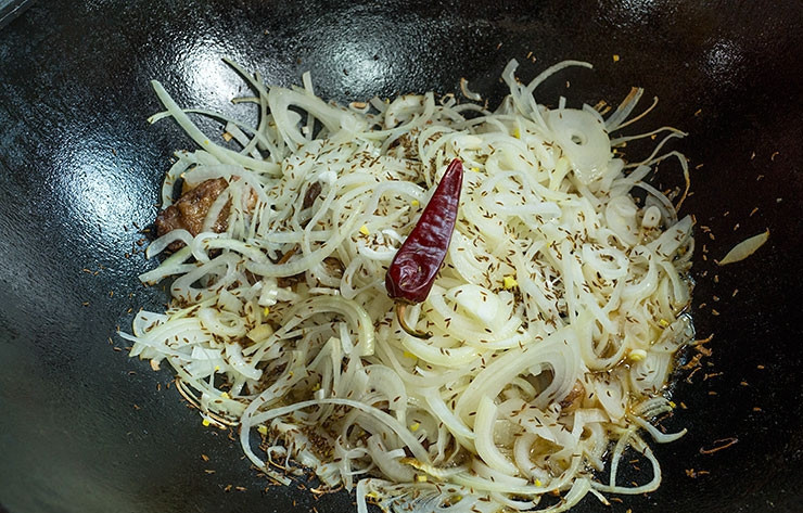 1. Этап. Бараньи ребрышки в казане: 4. Лук за это время очистить и порезать полукольцами. Ребра посыпать солью, зирой, кориандром и еще раз перемешать. Отправить лук на румяное мясо и, не перемешивая, приправить еще немного солью, специями и острым перцем. Накрыть казан крышкой и тушить ребрышки на медленном огне минут 40-50.