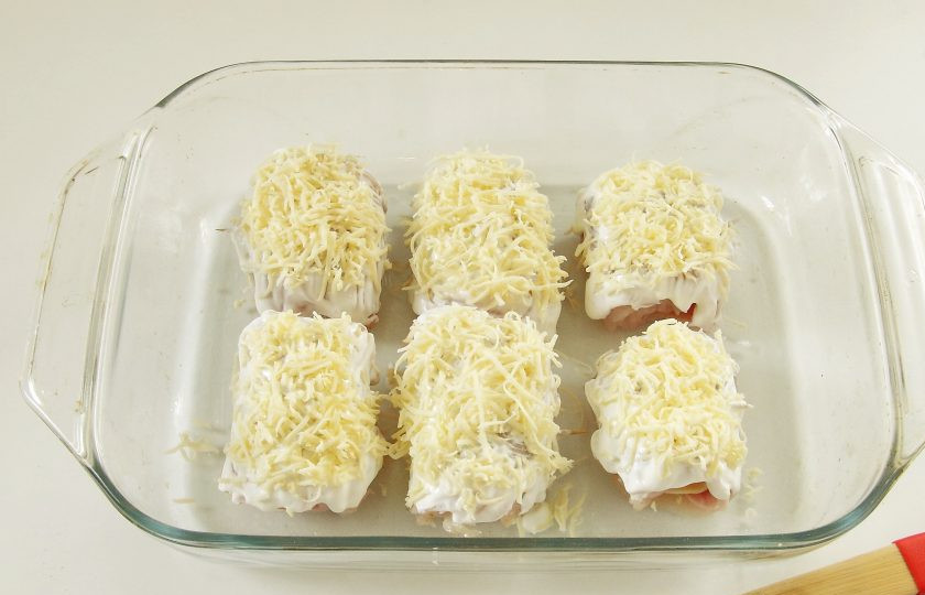 1. Этап. Куриные роллы с ветчиной и сыром: 6. Верх смажьте сметаной и посыпьте тертым сыром.