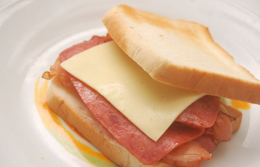 1. Этап. Сэндвич с беконом: Сложите все ингредиенты на ломтик хлеба в последовательности - сначала бекон, затем ветчину и сверху сыр. Накройте вторым ломтиком хлеба.