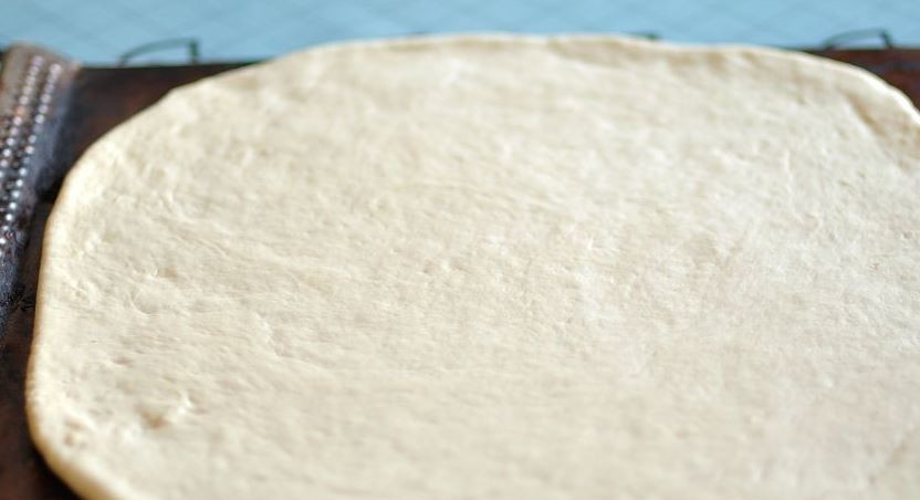 1. Этап. Домашняя пицца в духовке: Возьмите дрожжевое тесто для пиццы, разморозьте его, если оно лежало в морозилке, раскатайте тесто в пласт около 0,5 сантиметра толщиной. Выложите тесто на противень.