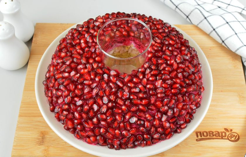 1. Этап. Салат Гранатовый браслет с курицей и яблоком: Очистите гранат, отделите зерна. Смажьте немного майонезом сверху салат, чтобы зерна лучше прилипали. В таком виде отправьте салат в холодильник для пропитки на часик.