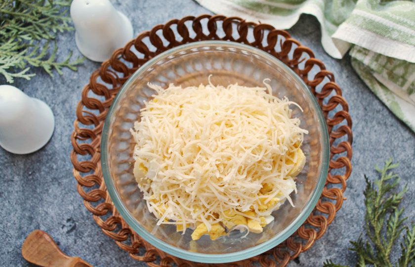 1. Этап. Салат из кальмаров с чесноком: Сыр натрите на крупной или средней терке и добавьте к кальмарам с яйцами.