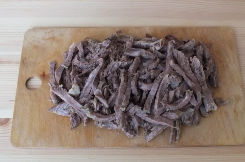 1. Этап. Салат Мужские слезы с говядиной: Говядину нарежьте соломкой. Посолите и добавьте перец. Перемешайте.