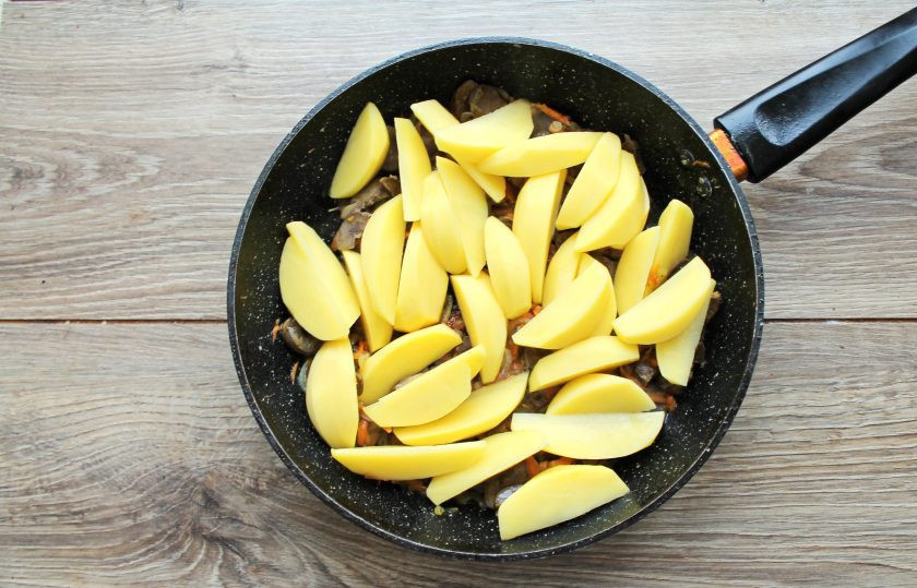 1. Этап. Говяжьи почки с картошкой: Картофель порежьте дольками и добавьте в сковороду с почками и овощами. Влейте в сковороду воду и перемешайте.