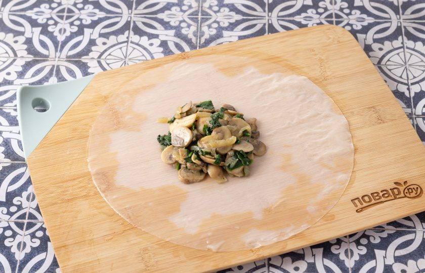 1. Этап. Блины из рисовой бумаги с шампиньонами: Лист рисовой бумаги размочите теплой водой, чтобы он стал мягким и эластичным. В центр выложите начинку из шампиньонов.