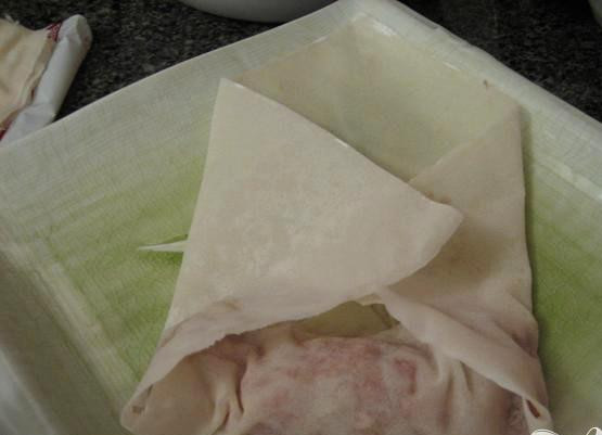 1. Этап. Блины с начинкой: 3. Возьмите лист теста, поместите начинку из говядины и овощей ближе к одному из уголков квадратного листа. Накройте начинку этим уголком, потом заверните боковые уголки. Затем скрутите тесто с начинкой в рол. Мокните пальцы в яичную смесь, и заклейте лист. Не стоит класть много начинки, иначе мясо не успеет приготовиться.