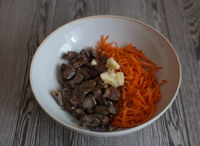 1. Этап. Куриные сердечки по-корейски: В салатник переложите куриные сердечки. Добавьте крупно раздавленный чеснок, специи и соль. Залейте горячим ароматным маслом. Закройте крышкой и оставьте не перемешивая на 20 минут.