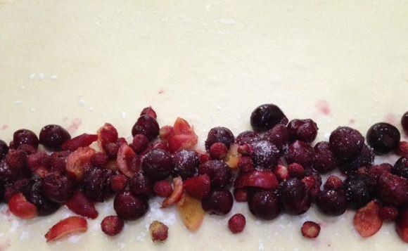 1. Этап. Слоеный рулет с вишней: Готовое слоеное тесто разморозьте и раскатайте как можно тоньше на посыпанной мукой поверхности. Если у вас нет готового теста, вы можете сделать его самостоятельно, но замороженное сэкономит ваше время. Посыпьте край теста крахмалом, который впитает лишний сок из ягод. Очищенные и промытые ягоды равномерно распределите по краю слоеного теста.