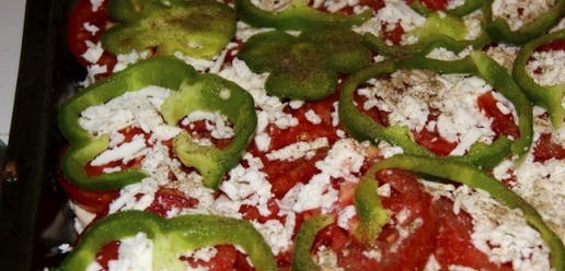 1. Этап. Деревенская запеканка по-гречески: Перец порезать тонкими кольцами и выстелить поверх помидоров. Сыр фета натереть на крупной тёрке и посыпать им всю поверхность запеканки.