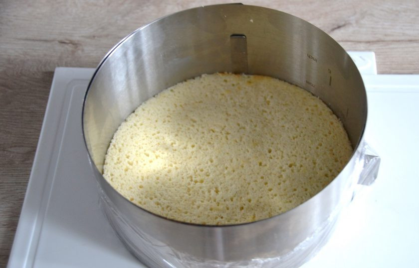 1. Этап. Торт Груши в карамели: Выложите вырезанный бисквит в кондитерское кольцо (диаметр 18 см.), низ которого затяните пищевой пленкой, установите кольцо на твердую поверхность.