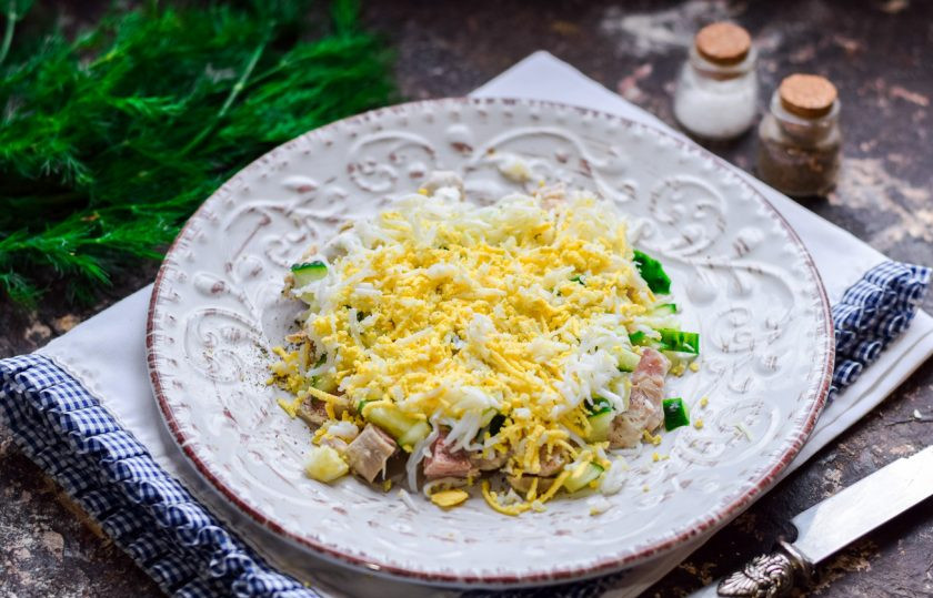 1. Этап. Салат Зимняя свежесть: Куриное яйцо очистите и натрите на мелкой терке. Выложите слой яиц поверх огурцов.