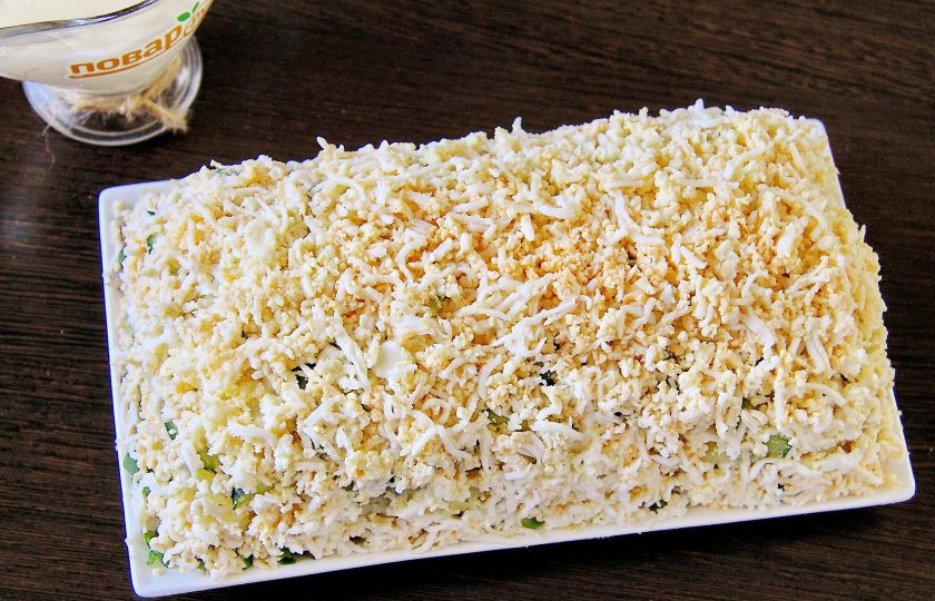 1. Этап. Салат Зеленая шуба: Последним слоем выкладываем тертые яйца, распределяя их равномерно по всей поверхности салата.