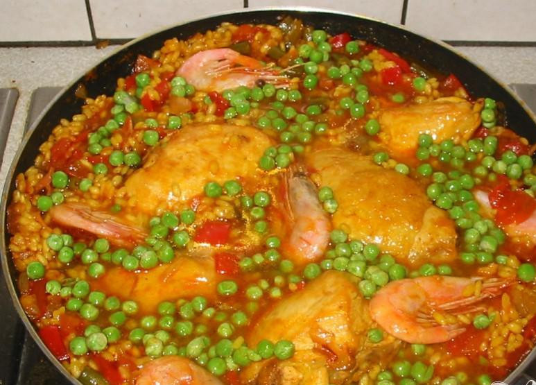 1. Этап. Традиционная испанская паэлья: 5. Нарезать фасоль. Добавить ее, кусочки курицы, горошек и тигровые креветки в паэлью. Готовить еще 20 минут. Помешивать паэлью каждые 5 минут, чтобы тигровые креветки приготовились со всех сторон. При необходимости добавить жидкости. Перед подачей на стол, попробовать рис, чтобы убедиться, что он полностью готов. При необходимости добавить еще соли и перца.