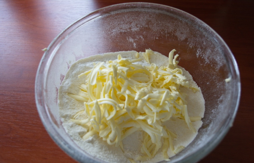 1. Этап. Печенье на кефире с вареньем: В миске просеять муку. Добавить натертое на терку холодное сливочное масло. Добавить сахар и разрыхлитель. Быстро руками смешать мучную смесь с маслом до состояния крошки.