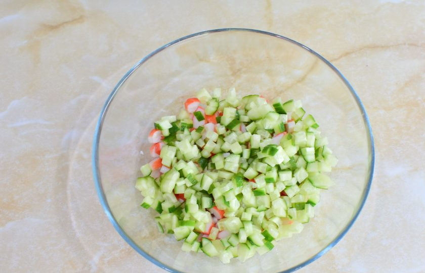 1. Этап. Крабовый салат с помидорами и огурцами: Следом нарежьте свежий огурец. Все ингредиенты нарезайте кусочками, примерно одинакового размера. Так салат будет смотреться гармоничнее.