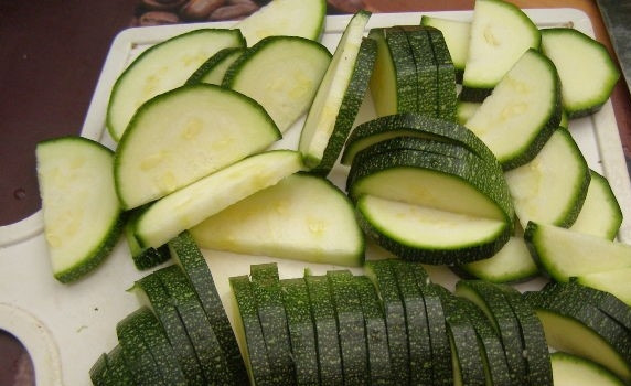 1. Этап. Салат с цукини: 2. Возьмите цукини. Помойте и порежьте полукольцами. Для этого разрежьте овощ вдоль, затем нарезайте нетолстыми полукольцами.